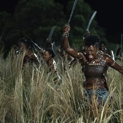 Nanisca (Viola Davis) och hennes armé av kvinnor kommer springande genom högt gräs med machete i händerna.