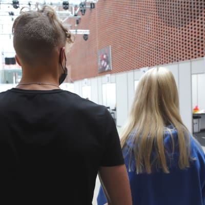 Kaksi nuorta seisoo selkä kameraa kohti ja odottaa rokotusvuoroaan Hämeenlinnan Verkatehtaalla.