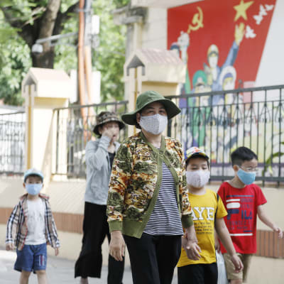 Kvinnor och barn på promenad i Hanoi på söndagen - alla utrustade med munskydd. 