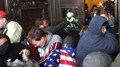 Demonstranter tänger sig igenom en av dörrarna till kongressbyggnaden i Washington