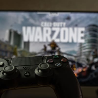 En playstationkontroll i förgrunden, i bakgrunden syns Call of Duty på tv:n.