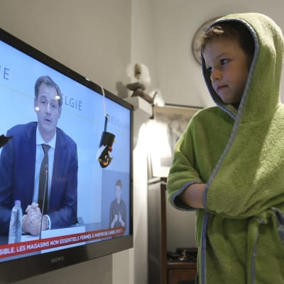 Pikkupoika katsoo televisiota, jossa Belgian pääministeri Alexander De Croo pitää puhetta.