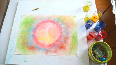 Teckning gjord med färgkritor i ljusa färger med en cirkel i mitten