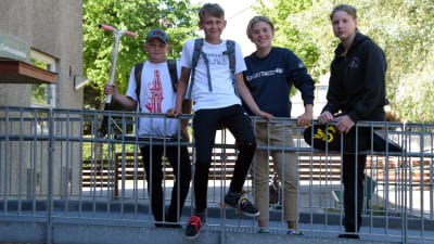 Fyra skolelever står på en gångbro och skrattar mot kameran. 