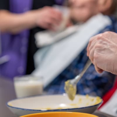Hoitajat syöttää vanhuksia Myyrmäen vanhustenkeskuksessa.