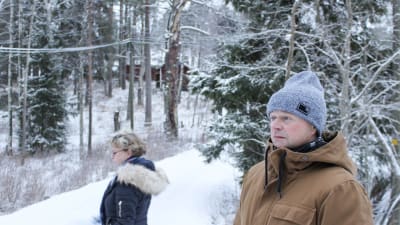 nicke står och funderar på en snöig väg, i bakgrunden syns anna-maija nordling och idyllisk vintermiljö