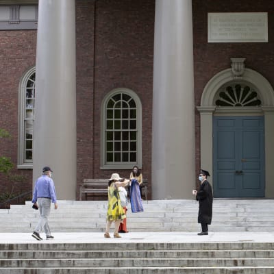 En student vid Harvard firar sin examen med sin familj under strikta coronaåtgärder, med  avstånd och ansiktskydd.