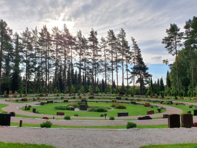 En begravningsplats med gravstenar och grönskade parkmiljö.
