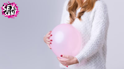 Kvinnan håller en luftballong vid sin mage