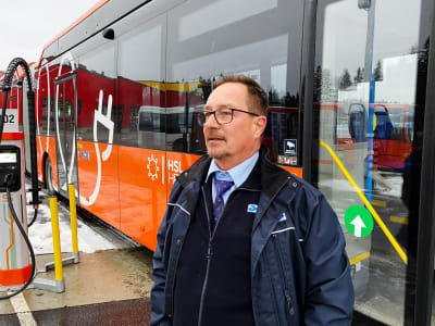 Frank Ahrenberg framför en orange elbuss.