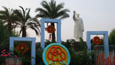 Staty föreställande Mao Zedong omgiven av palmer.