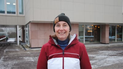 Kvinna med röd jacka och svart mössa.