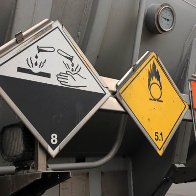 Syövyttävästä aineesta ja palovaarasta ilmoittavat varoitusmerkit säiliöauton kyljessä.