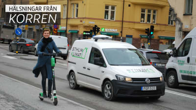En glad kvinna åker ett elrullbräde på en gata. På bilden är också texten "hälsningar från korren".