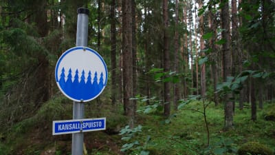 En skylt med texten "kansallispuisto" i en skog.
