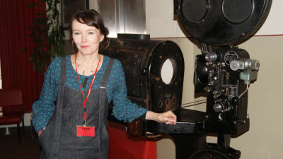 Marja Helander poserar vid gammal filmkamera.