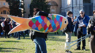 En person som bär på en färgglad sardinmodell.