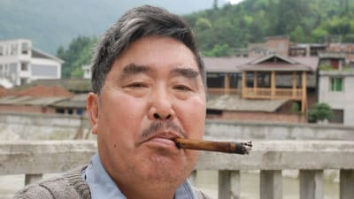 Kinesisk man röker cigarett med ett munstycke av bambu.