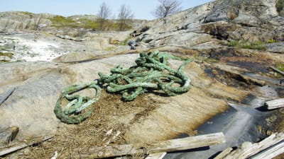 Ett tjockt rep ligger på marken på några klippor. Det ser ut att ha fallit från ett handelsfartyg.