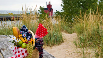 Ett slitet träbord med en picnickorg på en strandäng. I bakgrunden syns havet.