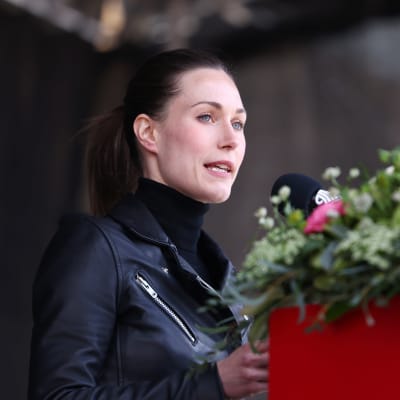 Sanna Marin i en talarstol prydd med blommor.
