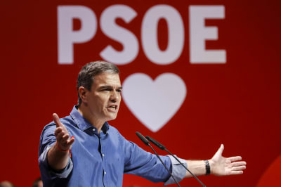 Pedro Sánchez håller tal mot en röd bakgrund med ett vitt hjärta.