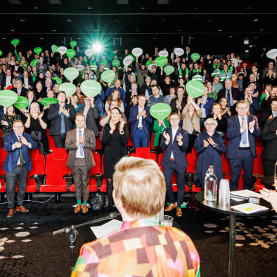 Centerpubliken applåderar efter sin ordförande Annika Saarikkos tal. Många håller också upp gröna pratbubblor i papp.