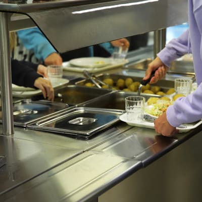 Hirvelän koulun oppilaat ottamassa kouluruokaa lautaselle ruokalinjastolla.