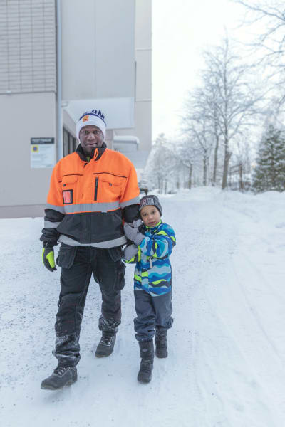 Lamin och Yaya kommer gående mot kameran utomhus. Yaya håller i Lamins underarm.