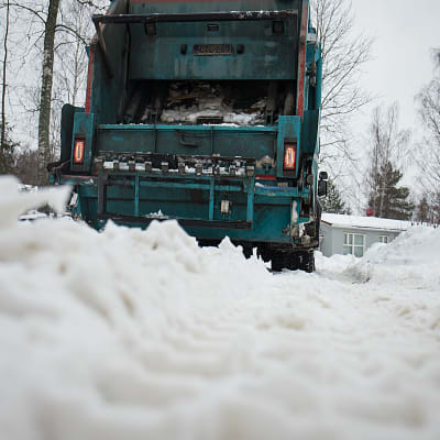 Jäteauto lumisella tiellä. 