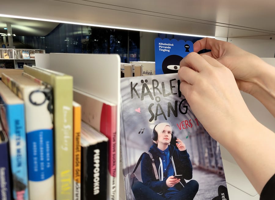 Händers som sätter fast ett blått märke på en bok i en bibliotekshylla.