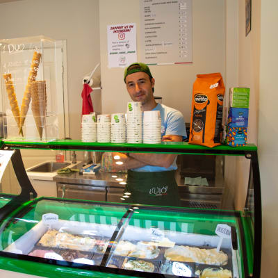 En leende man står bakom en frysdisk med glass i en butik.