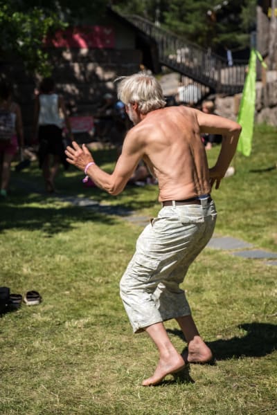 Selin kuvattu iäkäs mies ilman paitaa tanssimassa Natural High Healing Festivaalilla.