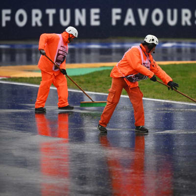 Miehet puhdistavat Imolan F1-rataa vedestä.