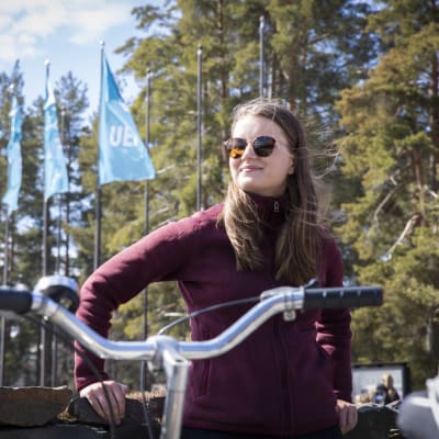 Maiju Eskelinen nojaa kiviaitaan aurinkoisella yliopiston kampuksella.