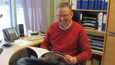 David Strömbäck sitter vid skrivbord bläddrar i katalog