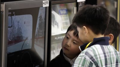Ett par barn i Kina betraktar ett videospel på en skärm i en butik.