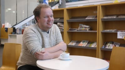 Masse Hellström sitter vid ett kaffebord i Kimito bibliotek