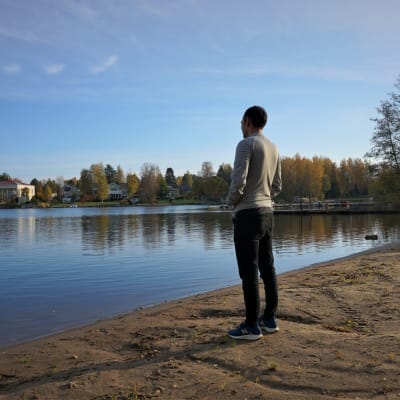 Ung man står vid vattnet.