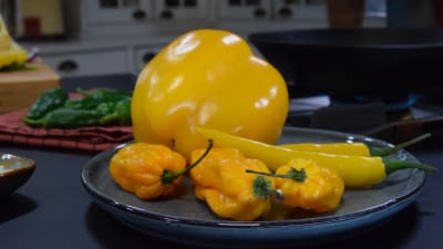 Keltaista chiliä ja paprikaa lautasella keittiössä
