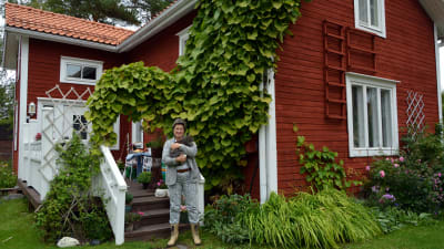 Porträtt av Lena Holmlund och hennes röda hus.