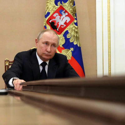 Vladimir Putin sitter vid ändan av ett bord.