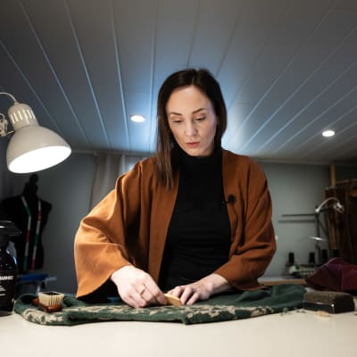 Kvinna vårdar en stickad tröja med en noppkam