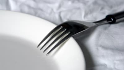 En gaffel på en tallrik på en vit duk.