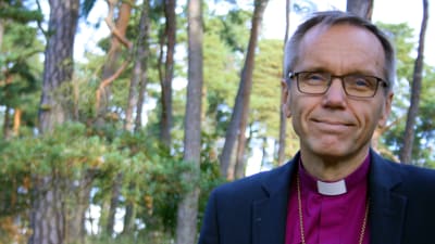 Närbild på biskop Björn Vikström fotad ute i naturen, skog i bakgrunden.