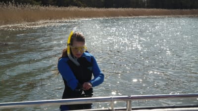 Linda Sandström iförd torrdräkt står i vattnet och bereder sig för snorkling