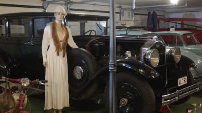 En stilig skyltdocka med minkkrage står bredvid en gammal bil i Geta nostalgi och motormuseum