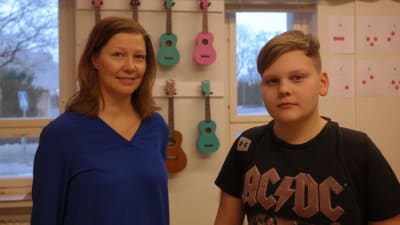 Musiklärare Micaela Sundström och hennes elev Alexander Helsender står framför en vägg med färgglada ukulelen