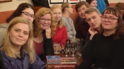 Några studenter iklädda overaller sitte vid ett bord på After Work