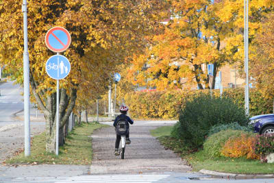 Ett barn kör med cykel längs med en trottoar i Närpes.